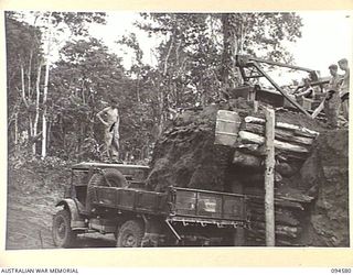 BOUGAINVILLE, 1945-07-31. TROOPS OF 15 FIELD COMPANY, ROYAL AUSTRALIAN ENGINEERS, USING BULLDOZER TO LOAD TRUCKS WITH SAND FROM A "CHINAMAN" AT A SAND PIT WEST OF THE OGORATA RIVER. IDENTIFIED ..