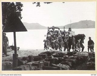 PIEDU ISLAND, BOUGAINVILLE AREA. 1945-09-29. JAPANESE PERSONAL GEAR STACKED ON THE BEACH IN READINESS FOR SEARCHING BY FIELD SECURITY PERSONNEL. JAPANESE TROOPS ARE UNLOADING AUSTRALIAN BARGE IN ..