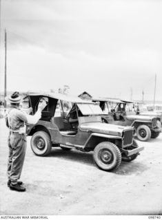 CAPE WOM, NEW GUINEA. 1945-11-14. VISITING JEEPS AT HEADQUARTERS 6 DIVISION BEING LINED UP BY CORPORAL R.W. SANDS, 6 DIVISION PROVOST COMPANY, WHO IS ON PROVOST DUTY