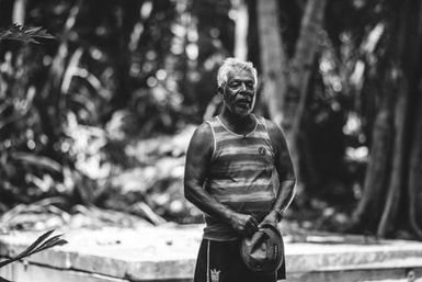 Black and white image of man standing infront of waterwell, Atafu, Tokelau