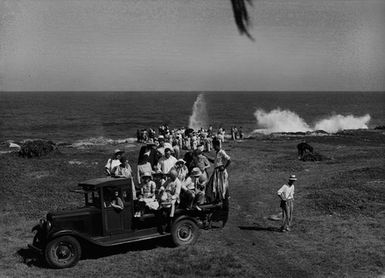 [A group of people watching waves crash against coastline]