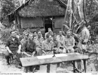 KIRIWINA, TROBRIAND ISLANDS, PAPUA. C. 1943-12. THE REVEREND R. S. CORRELL OF ADELAIDE, SA, CHAPLAIN, CONDUCTING AN OUTDOOR SERVICE AT NO. 14 WIRELESS TELEGRAPHY STATION RAAF