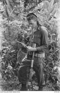 BOUGAINVILLE ISLAND. 1945-02-13. Q149974 PRIVATE M. HENDERSON, NO.8 PLATOON, A COMPANY, 61ST INFANTRY BATTALION READING A LETTER FROM HOME SOON AFTER HIS RETURN FROM A PATROL IN THE WARAPA AREA