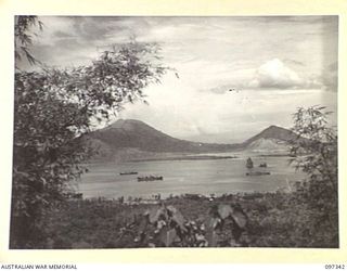 RABAUL, NEW BRITAIN. 1945-09-29. SIMPSON HARBOUR VIEWED FROM THE HILLS NEAR FOUR WAYS. THE VIEW SHOWS THE MOTHER CRATER, LEFT; TO THE SOUTH, DAUGHTER AND MATAPI ON THE RIGHT. LIBERTY SHIPS BRINGING ..