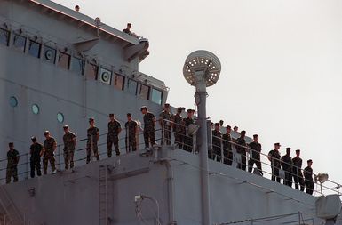 US Marine Corps (USMC) personnel man the rails of the USS FORT MCHENRY (LSD 43) as the ship is moored to the Sierra Pier at Guam, during Exercise TANDEM THRUST 99