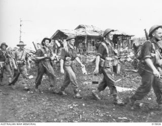 1943-09-25. NEW GUINEA. FALL OF LAE. AUSTRALIAN TROOPS FILE INTO BOMB BLASTED LAE