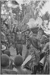 Pig festival, wig ritual: woman holding flowers dances around wigged men, exclaiming on their beauty