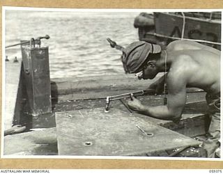 LAE, NEW GUINEA, 1943-11-05. ASN-32787887 T/5 B.S. ELMO OF THE 1052ND ENGINEERS PORT CONSTRUCTION AND REPAIR GROUP FLAME CUTTING A STEEL PLATE TO BE USED IN THE CONSTRUCTION OF THE FIRST LIBERTY ..