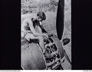 MILNE BAY, PAPUA, 1943-05. AN ARMOURER FROM NO. 100 SQUADRON RAAF SITTING ON AN ENGINE COWLING OF ONE OF THE SQUADRON'S BRISTOL BEAUFORT BOMBERS, AS HE WORKS ON THE ENGINE. THE AIRCRAFT, PROBABLY ..