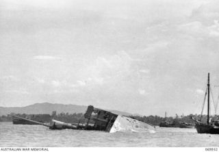 GILI GILI, MILNE BAY, NEW GUINEA. 1942-12. THE CARGO STEAMER "ANSHUN", WHICH WAS SUNK BY SHELLFIRE FROM A JAPANESE CRUISER WHILE UNLOADING AT GILI GILI WHARF ON THE 1942-09-06, DURING THE BATTLE ..