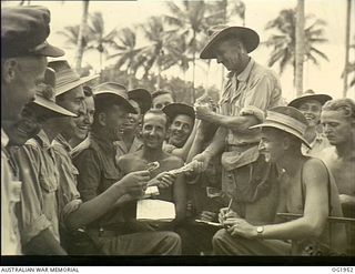 MADANG, NEW GUINEA. C. 1944-10. NEW GUINEA. FIVE TO ONE THE FIELD. TEMPORARY BOOKMAKER 77842 LEADING AIRCRAFTMAN S. COWELL, PIALBA, QLD, DOES A ROARING TRADE LAYING THE ODDS AT A RAAF SPORTS ..