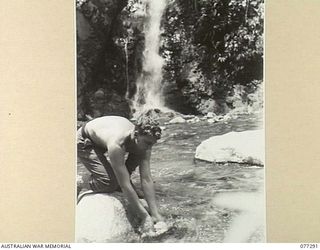 LARUMA VALLEY, BOUGAINVILLE ISLAND. 1944-11-25. V503314 CORPORAL M.W. PATTISON, 2ND FIELD SURVEY COMPANY WASHING HIS CLOTHES IN THE LARUMA RIVER NEAR THE HEADQUARTERS OF THE 9TH INFANTRY BATTALION