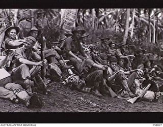 LANGEMAK BAY, NEW GUINEA. 1943-10-20. PERSONNEL OF THE 2/24TH AUSTRALIAN INFANTRY BATTALION RESTING ON THE BEACH WHILE WAITING FOR THEIR LANDING CRAFT TO TAKE THEM TO LAUNCH JETTY. SHOWN: VX28608 ..