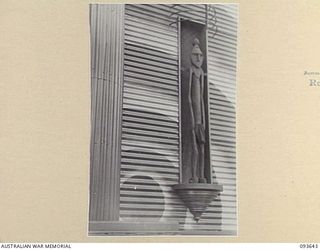 MALMAL VILLAGE, JACQUINOT BAY, 1945-07-03. A NATIVE CARVED MALE FIGURE, PLACED IN THE RIGHT HAND PANEL OF THE NEWLY COMPLETED THEATRE STAGE AT HEADQUARTERS 5 DIVISION. THE THEATRE WAS DESIGNED ON ..