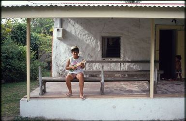 Child playing ukelele on bench