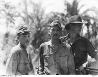BABIANG AREA, NEW GUINEA, 1944-11-18. TWO JAPANESE SERGEANTS, CAPTURED BY THE 2/10 COMMANDO SQUADRON AT SUAIN IN A WEAKENED CONDITION, RECEIVE ESCORT TO ALLIED TRANSLATOR INTERROGATION SECTION ..