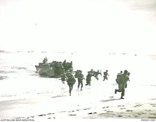 THE SOLOMON ISLANDS, 1945-01-13. TROOPS HURRYING ASHORE FROM A LANDING CRAFT AT A BOUGAINVILLE ISLAND BEACH. (RNZAF OFFICIAL PHOTOGRAPH.)