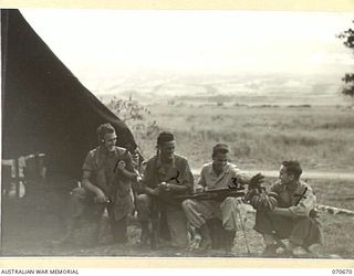 KELANOA, NEW GUINEA, 1944-02-25. TROOPS OF THE U.S. 532ND AMPHIBIOUS ENGINEERS, ("9TH DIVISION NAVY") ATTACHED TO THE 5TH AUSTRALIAN DIVISION, PICTURED CLEANING RIFLES AND EATING BANANAS OUTSIDE ..