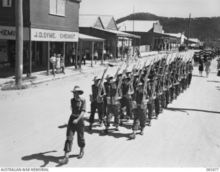 HERBERTON, QLD. 1944-04-25. THE 3RD PLATOON OF PERSONNEL OF THE 6TH DIVISION, MARCHING ALONG THE MAIN STREET TO THE WAR MEMORIAL FOR THE ANZAC DAY CEREMONY. IDENTIFIED PERSONNEL ARE:- SX7095 ..