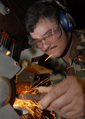 US Navy PETTY Officer 2nd Class Rodney Rodriguez, a Seabee assigned to Naval Facilities Engineering Command Marianas, grinds a six-inch bolt at Naval Base Guam. The bolts will be used for a base renovation project at Naval Base Guam. (U.S. Navy photo by Mass Communication SPECIALIST 2nd Class John F. Looney) (Released)