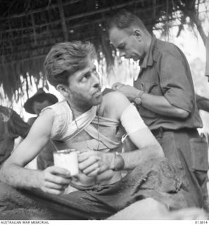 1942-12-11. PAPUA - GONA. AN AUSTRALIAN OFFICER, WHO HAS JUST CRAWLED IN AFTER LYING EIGHT DAYS WOUNDED NEAR JAPANESE LINES, RECEIVES MEDICAL TREATMENT. HE WAS ONLY A FEW FEET AWAY FROM THE ..