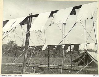 LAE, NEW GUINEA. 1944-09-06. DOZENS OF SMALL SHEETS OF TENTAGE MATERIAL EXPOSED TO THE WEATHER AFTER BEING SUBJECTED TO VARIOUS TYPES OF WATER PROOFING AND DAMP PROOFING. THESE TESTS ARE BEING ..