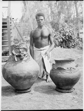 Man kneeling between two large sago pots brought to trading store, Awar, Sepik River, New Guinea, 1935, 2 / Sarah Chinnery