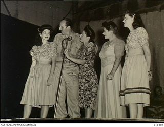 Bougainville. New Guinea. 1945. Bob Dyer, a radio comedian, and women singers from his concert party on stage entertaining troops in Bougainville