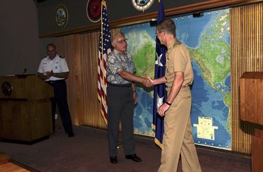 US Navy (USN) Admiral (ADM) Dennis Blair (right), Commander-in-CHIEF, USN Pacific Command, shakes hands with Paul Stankiewicz, CHIEF Editor, Asia/Pacific Defense Forum Magazine, during the publications 25th Anniversary Ceremony. Pictured at the podium is US Air Force (USAF) Lieutenant Colonel (LTC) Joe Screnci, Manger of the Forum