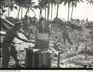 LOS NEGROS ISLAND, ADMIRALTY ISLANDS. 1944-03-18. RAAF AIRMEN WATCH LIEUTENANT ALAN MOORE (LEFT), OFFICIAL WAR ARTIST, A MEMBER OF THE AIF AT PRESENT WORKING WITH THE RAAF ON LOS NEGROS ISLAND, ..