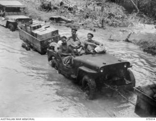 A jeep and trailer of the 9th Infantry Battalion, loaded with stores, ploughing through the mud and slush of the Mosigetta Road. Identified personnel are: (left to right) QX57464 Driver L Coomer; ..