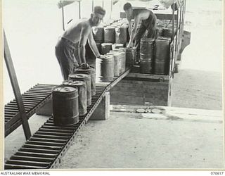 PORT MORESBY, PAPUA, 1944-02-25. VX109776 DRIVER D. GINNIVAN (1) AND VX74946 DRIVER D. THIEL (2), MEMBERS OF THE 126TH GENERAL TRANSPORT COMPANY, LOAD 4-GALLON CANS ONTO A VEHICLE AT THE 1ST ..