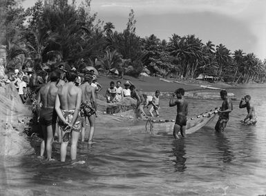 [View of Pacific island men holding a fishing net]