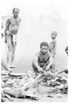 Group gathered around pieces of pig ready for distribution