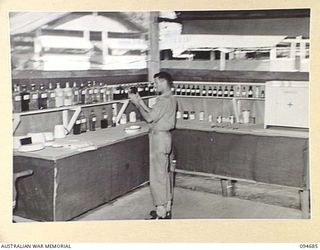 YALU, NEW GUINEA. 1945-08-03. SERGEANT L.E. PEARCE PREPARING A MIXTURE AT THE REGIMENTAL AID POST, NEW GUINEA TRAINING SCHOOL