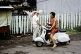 French Polynesia, woman driving scooter with child on Tahiti Island