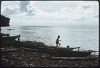 Child plays on beached canoes