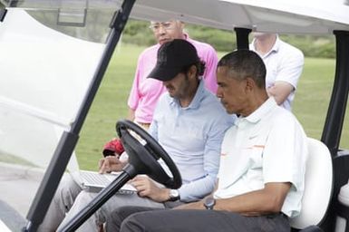 Barack Obama confers with Robert Baker after he plays golf in Kaneohe Bay, Hawaii, December 24, 2014