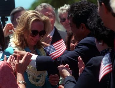 A close up view of First Lady Hillary Clinton as she is greeted on her arrival by the crowd waving United States flags. She is here for the commemoration of the 50th anniversary of World War II