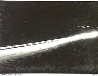 PORT MORESBY, NEW GUINEA. 1943-06-26. NIGHT PHOTOGRAPH OF CONVOY OF HEAVY TRUCKS MOVING ALONG PORT MORESBY ROAD