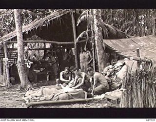 NADZAB AIRSTRIP, NEW GUINEA. 1943-09-18. THE NADZAB AIRSTRIP EVACUATION CENTRE. THE OFFICER COMMANDING, 9TH AUSTRALIAN FIELD AMBULANCE, NX108152 MAJOR T. HOLCOMBE CAN BE SEEN WEARING A STETHOSCOPE ..