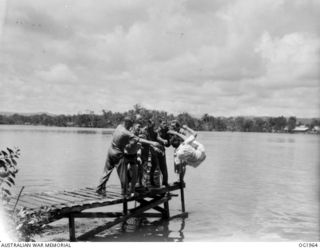 MADANG, NEW GUINEA. C. 1944-12. CHRISTMAS SPIRIT WAS IN EVIDENCE AT RAAF MEDICAL RECEIVING STATION IN NEW GUINEA. NURSES BEING TOSSED FROM A JETTY INTO THE HARBOUR