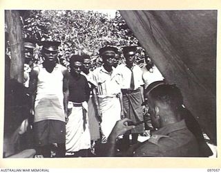 MATAPI, RABAUL, NEW BRITAIN. 1945-09-20. MAJOR C.D. BATES, DISTRICT OFFICER, AUSTRALIAN NEW GUINEA ADMINISTRATIVE UNIT INTERROGATING A GROUP OF VILLAGE CHIEFS WHO HAVE BEEN CALLED FROM VILLAGES IN ..