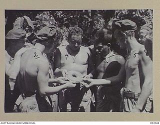 BOUGAINVILLE. 1945-05-16. MEMBERS OF 24TH INFANTRY BATTALION INSPECTING THE BASE PLATE OF AN RNZAF BOMB WHICH LANDED IN A C COMPANY POSITION DURING THE BOMBING OF JAPANESE ALONG THE BUIN ROAD SOUTH ..