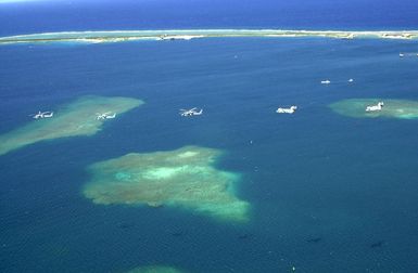 Two UH-46 Sea Knights and three UH-60 Black Hawk helicopters assigned to Andersen Air Force Base (AFB), Guam, fly over the Pacific Ocean, near their home