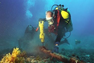 MASTER CHIEF (UCCM) Michael R. Oliver of Underwater Construction Team Two (UCT-2) drills holes in the coral bed alongside an underwater cable to install clamps to stabilize the cable at the Pacific Missile Range Facility off Kauai, Hawaii