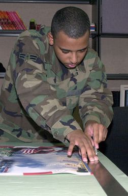 US Air Force (USAF) AIRMAN First Class (A1C) Robert Smith, cuts a presentation out at Andersen Air Force Base (AFB), Guam. AIRMAN Smith is a part of the multimedia section, which contains photo, video, and graphics