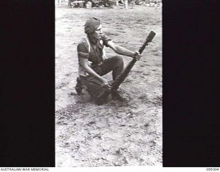 RABAUL, NEW BRITAIN, 1945-12-06. A SOLDIER ARMED WITH A GRENADE DISCHARGER CUP ATTACHED TO A .303 INCH RIFLE FIRES FROM THE GROUND DURING A DEMONSTRATION OF VARIOUS INFANTRY WEAPONS. THIS POSITION ..