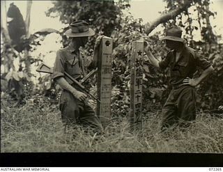 YAULA, NEW GUINEA. 1944-04-08. AN ARMY CAPTAIN SERVING AS A WAR CORRESPONDENT (1), WITH VX93433 CAPTAIN W. DARGIE, OFFICIAL WAR ARTIST, MILITARY HISTORY SECTION (2), EXAMINING THE INSCRIPTIONS ON ..