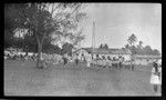 School children with arms up, while others look on, school in background